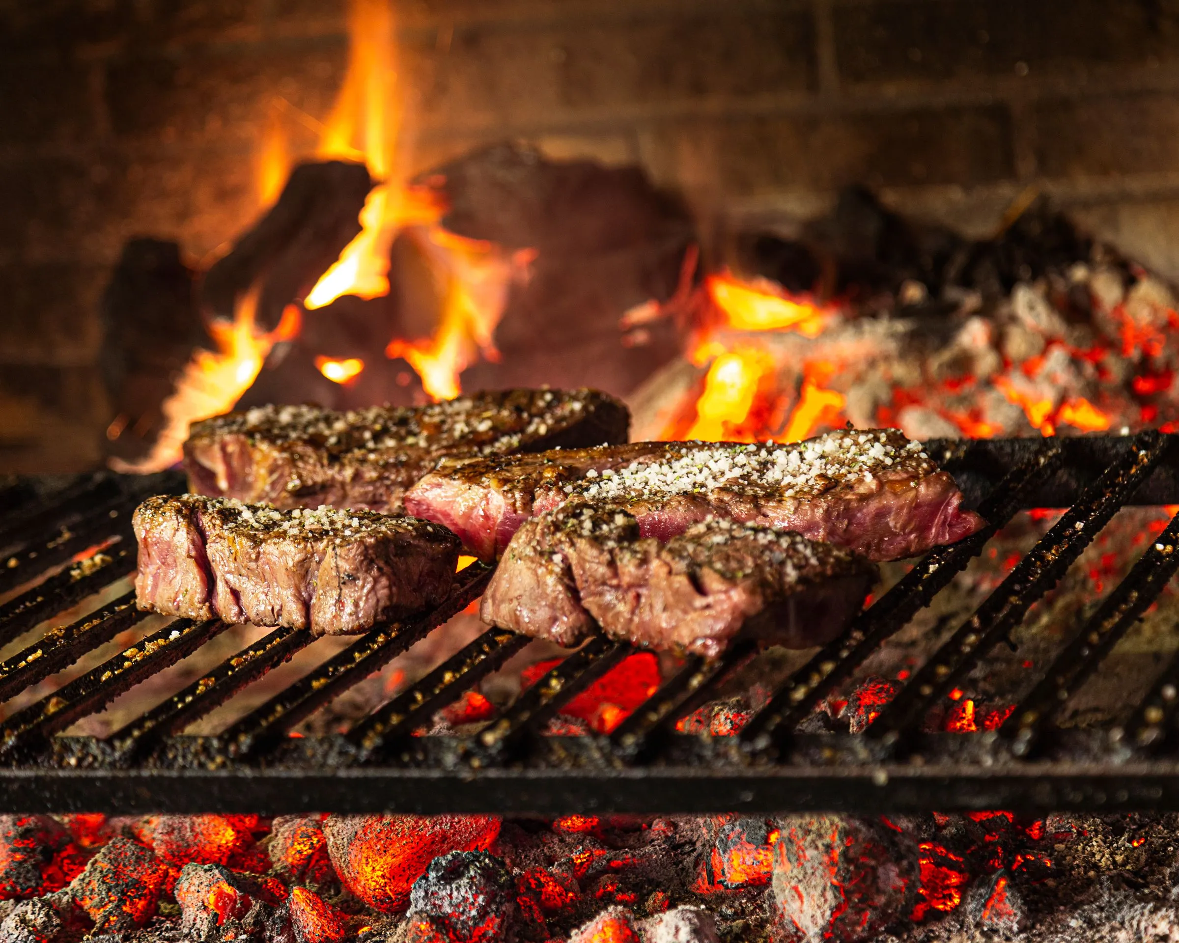 Txuletas de vaca vieja asándose sobre brasa de leña en la parrilla de Asador Artebe