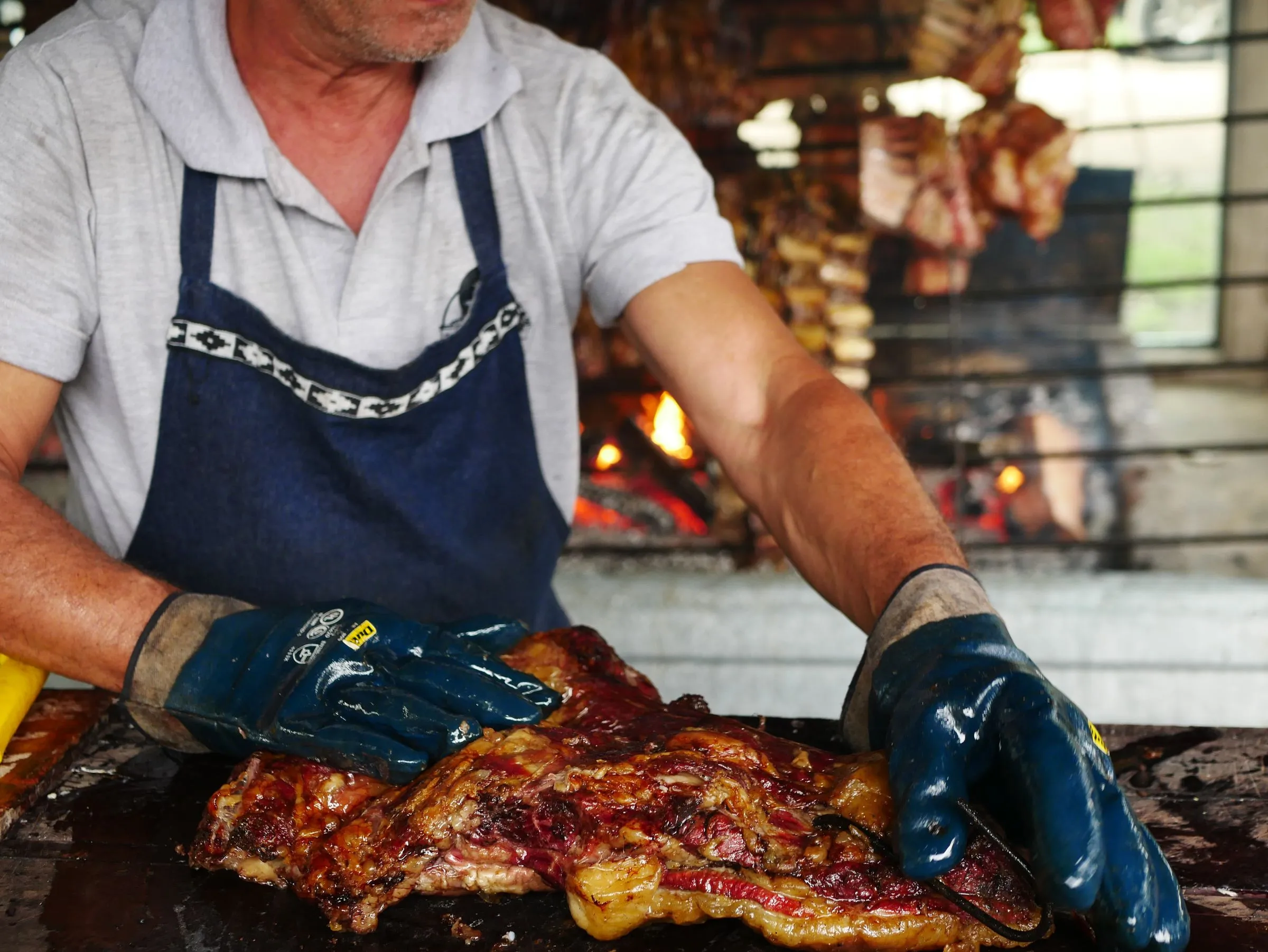 El parrillero de Asador Artebe sacando la carne del horno de brasa con las manos protegidas